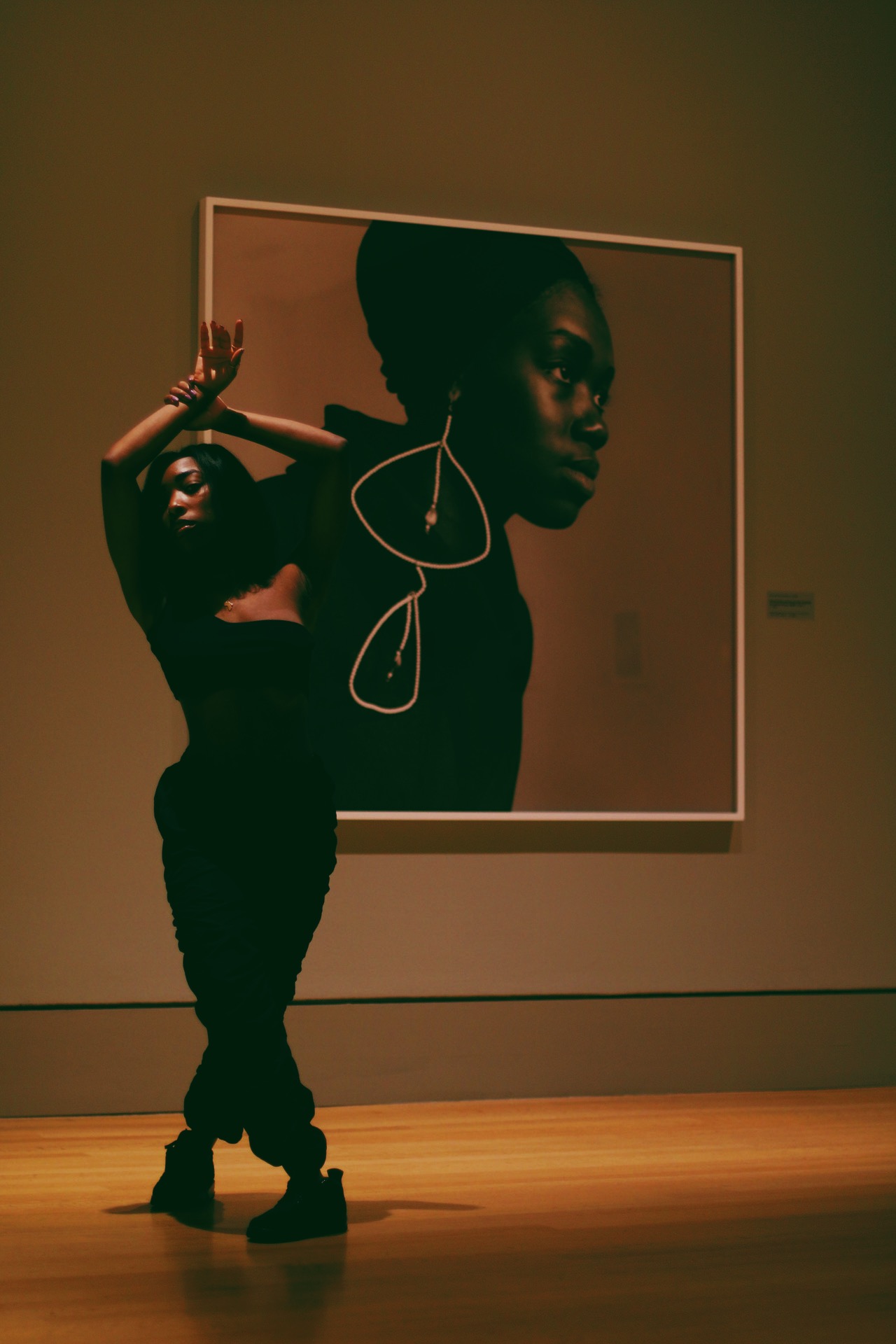 Female figure with arms raised posing in front of Kwame Brathwaite photograph