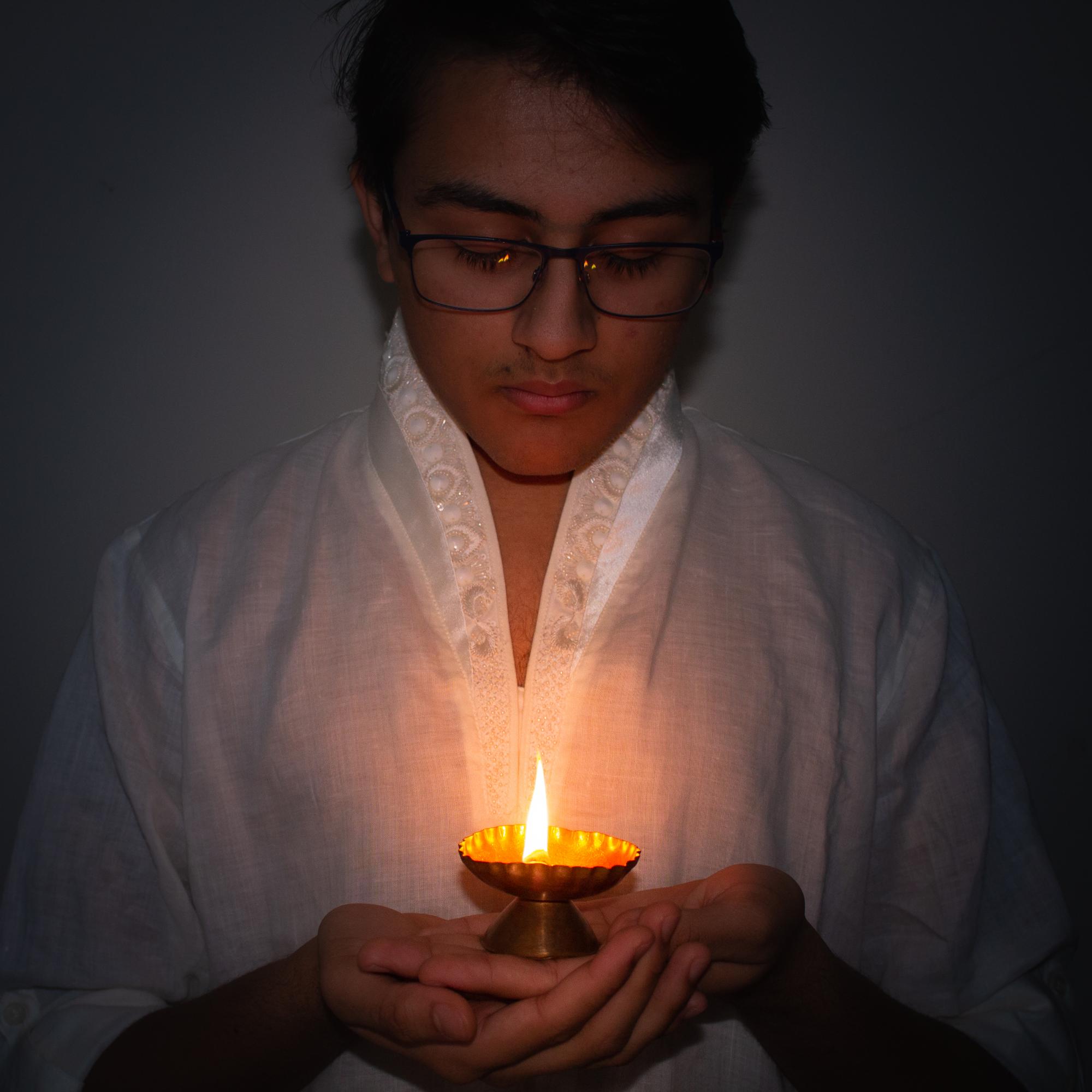 A young man looks into a flame in hopes of a better future, and a for the wellbeing of his family and others, while wearing a traditional Indian Kurta. 
