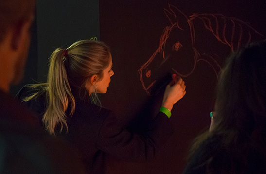woman drawing a horse with chalk on the wall in the loft