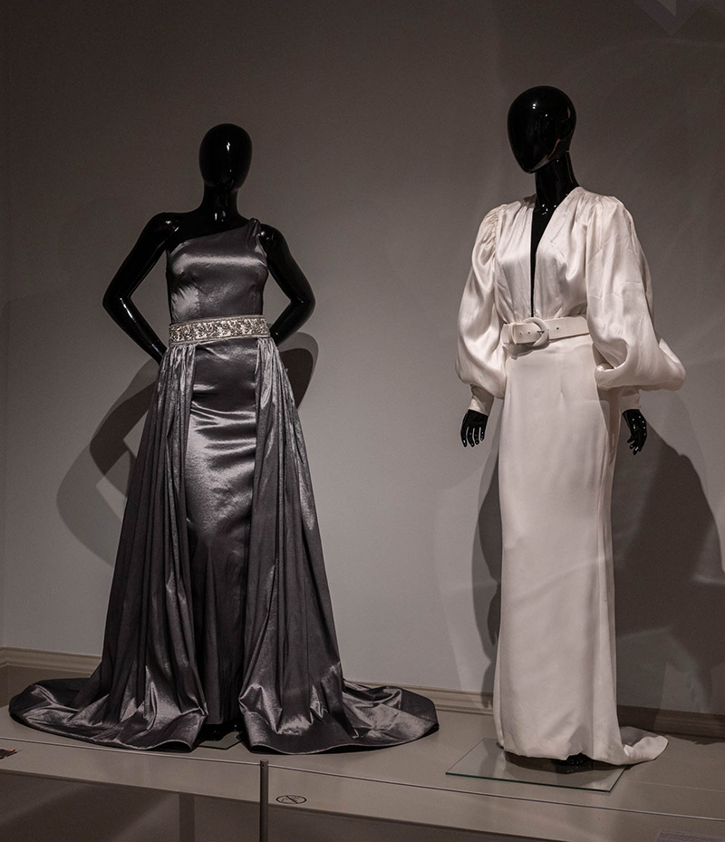 Two mannequins, one in a steel grey sleeveless gown and the other in a white, long-sleeved wedding gown