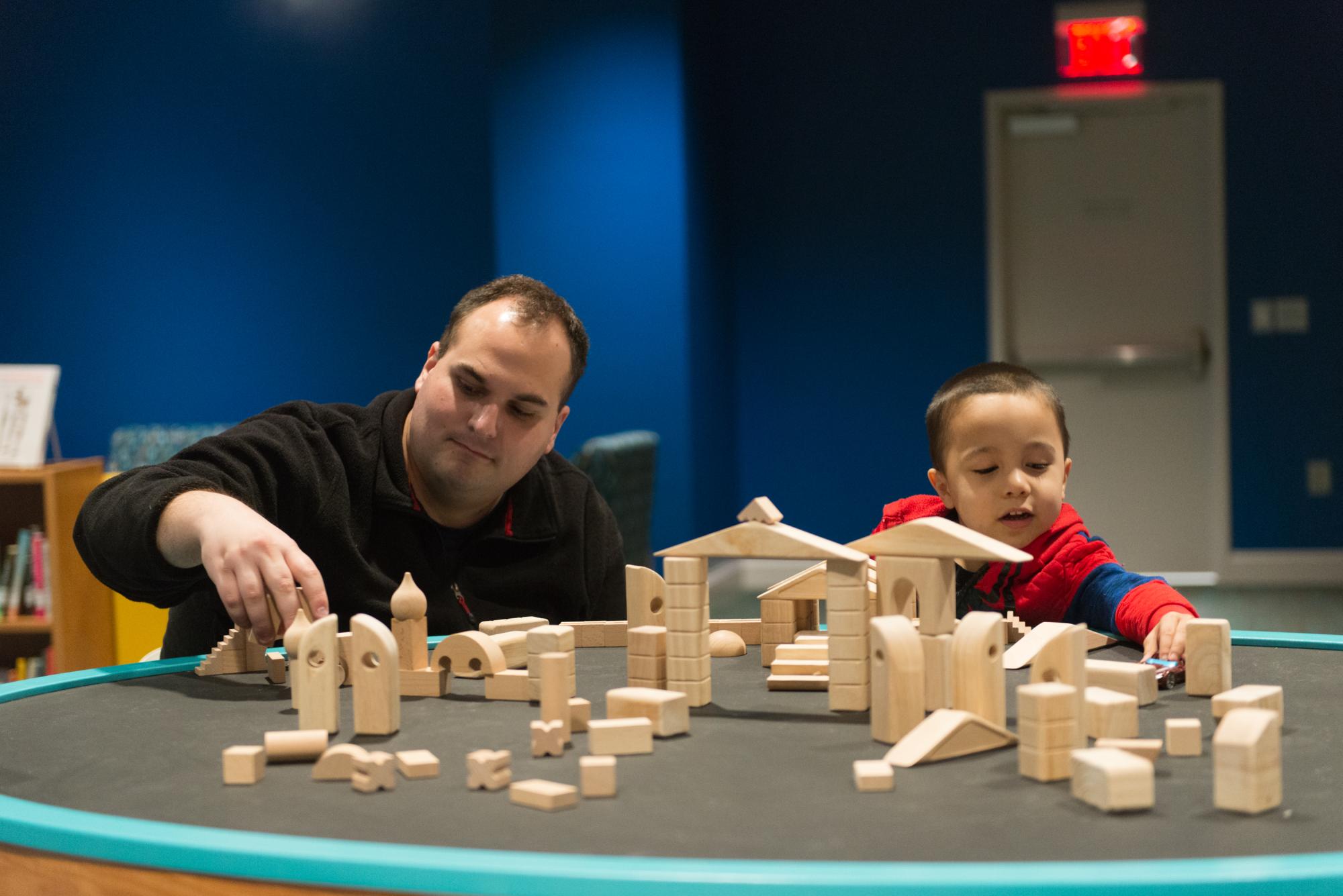 Father and son building together with wooden blocks