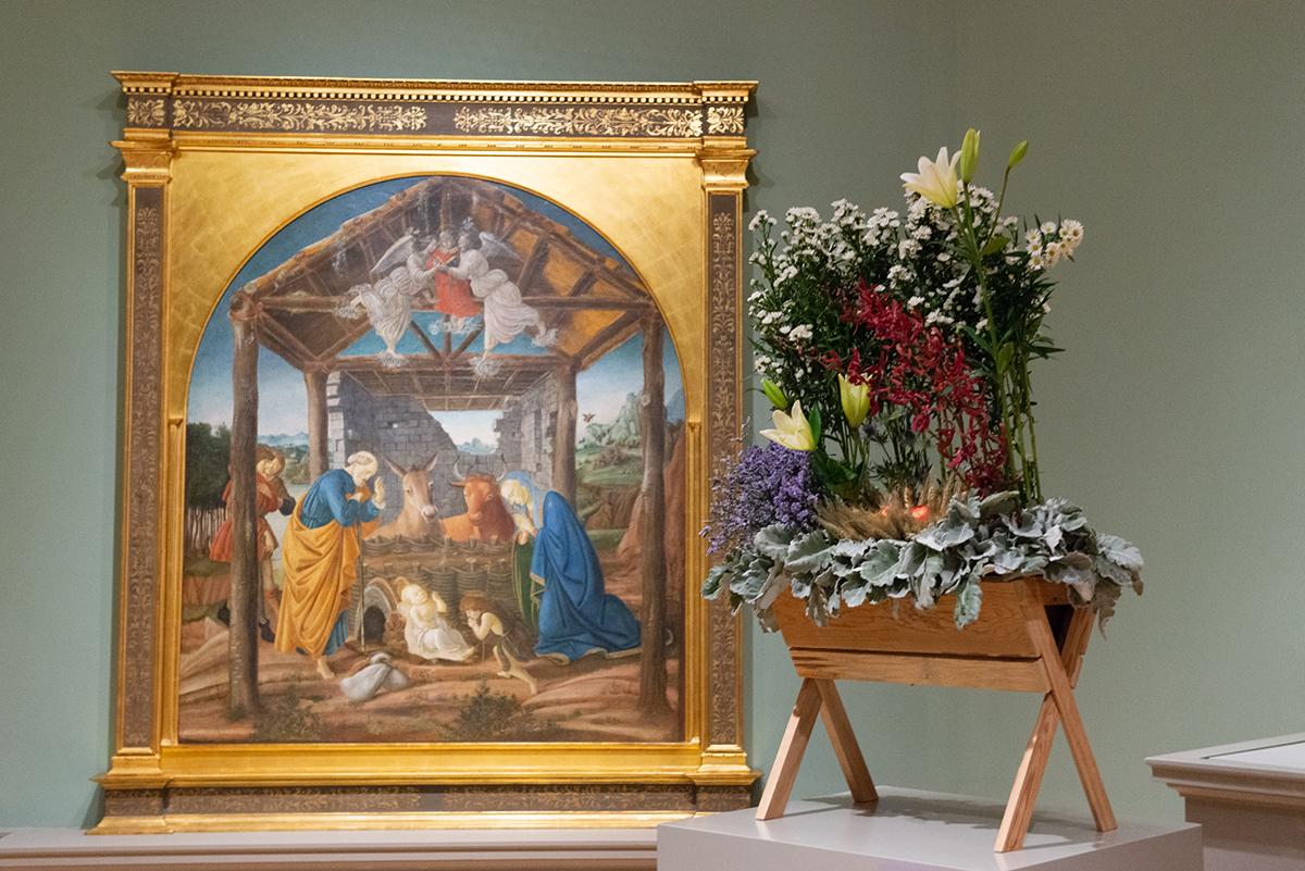 A framed painting next to a flower stand