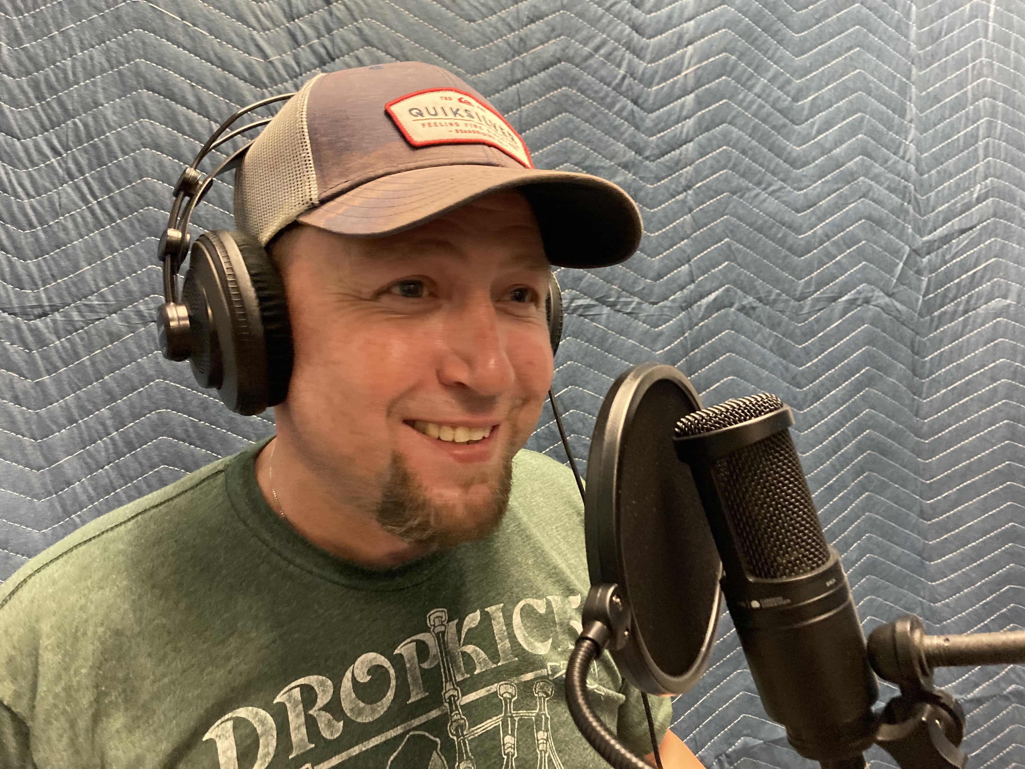 Binder podcast host Ray McManus smiling and talking into a microphone during production.