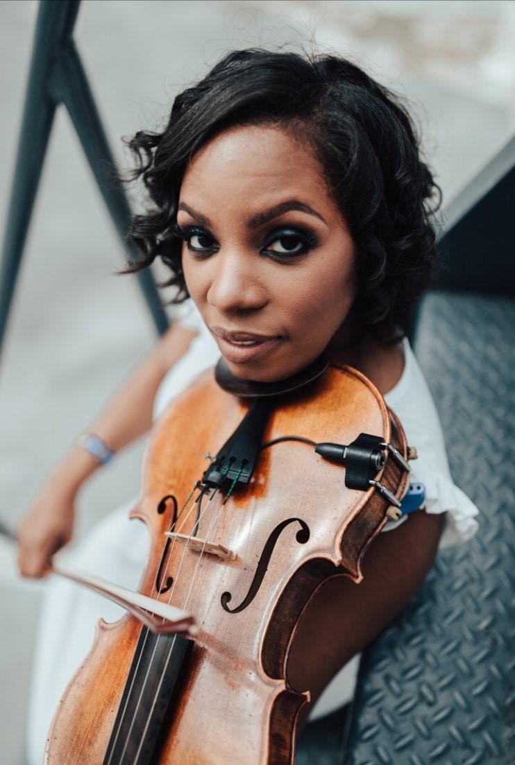 Closeup image of Nicole Neely looking to the camera while playing her violin 