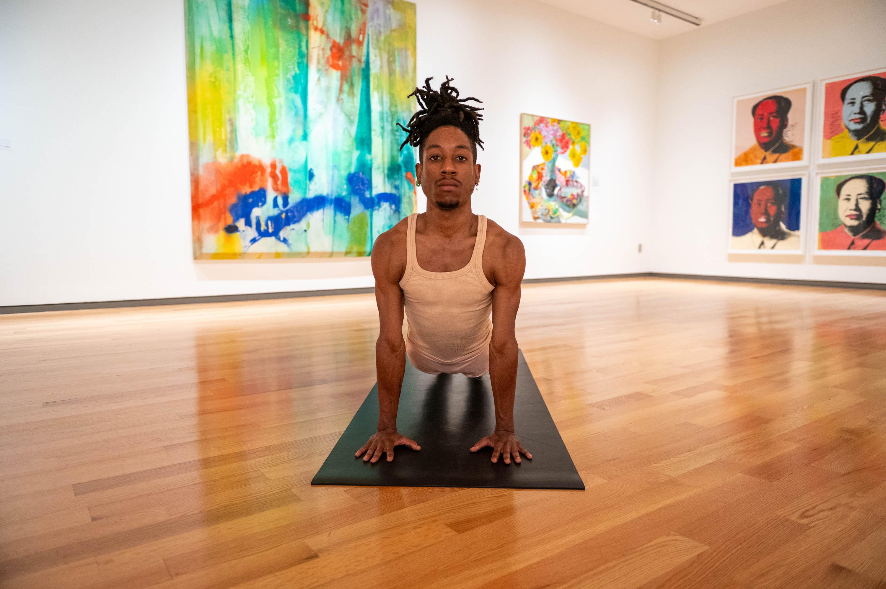 Dre Drummond in yoga pose in Gallery 20 with colorful paintings in background