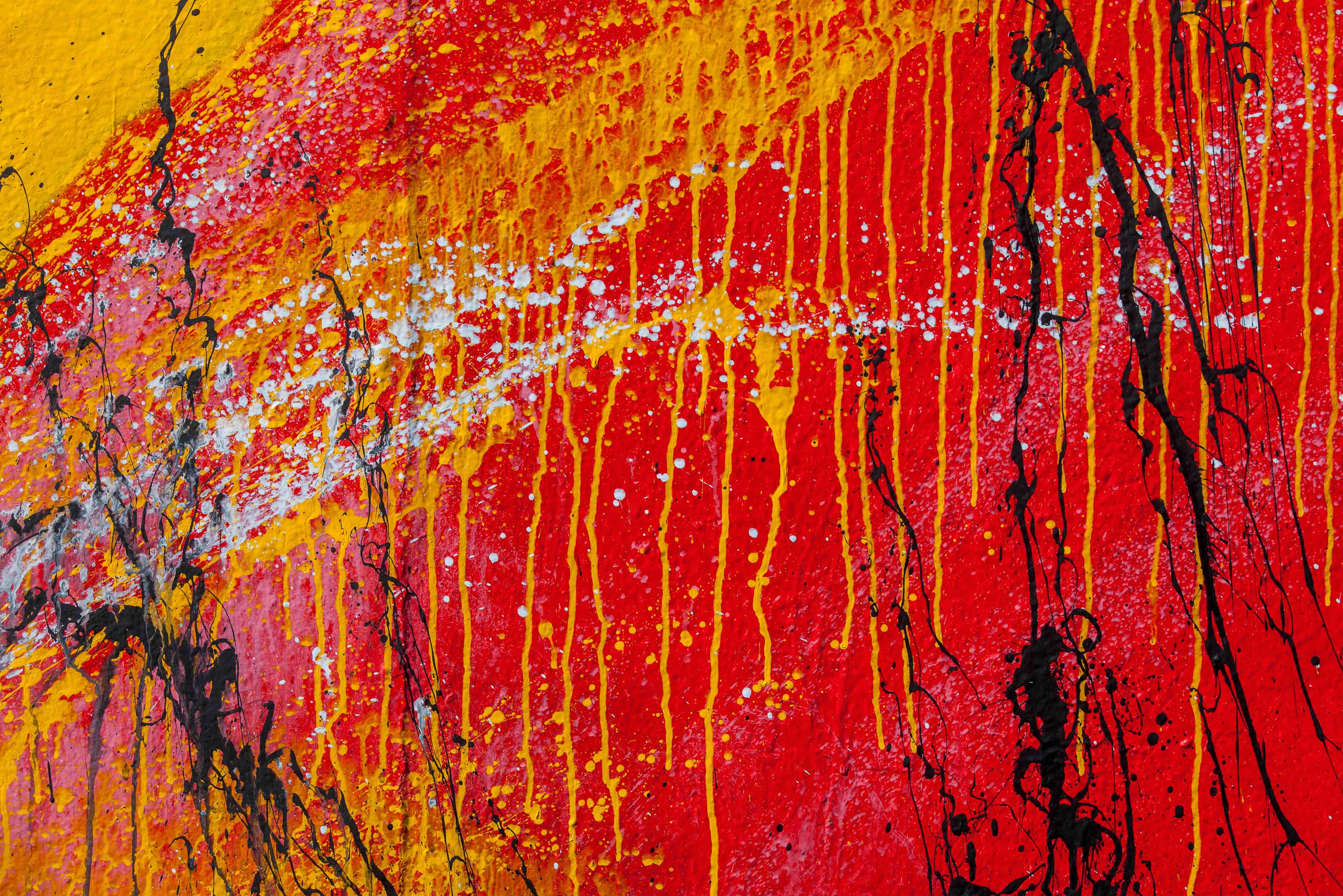 Red abstract painting with white, yellow, and black splatter and drip patterns