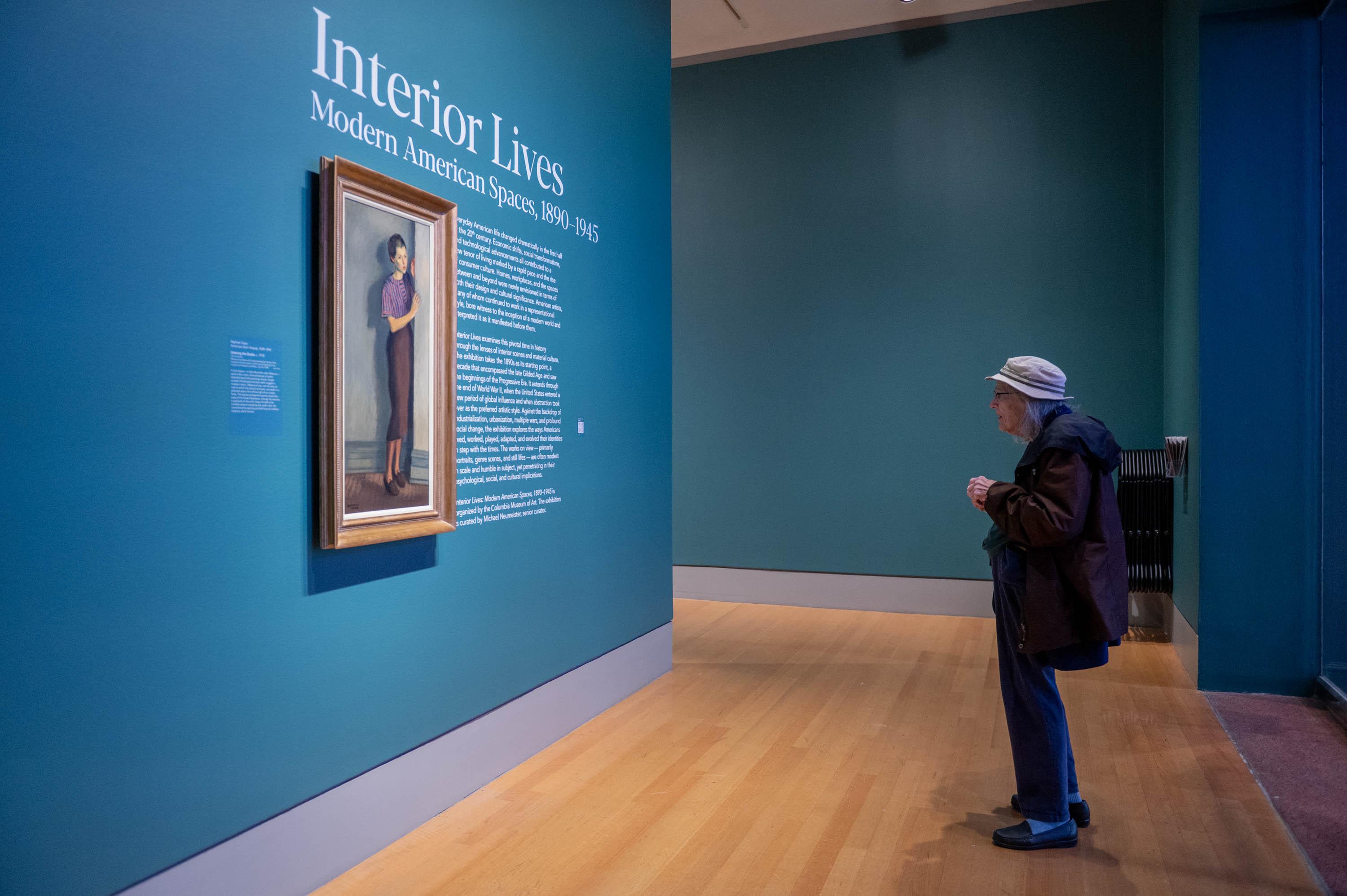 Visitor standing at the title wall for Interior Lives Exhibition