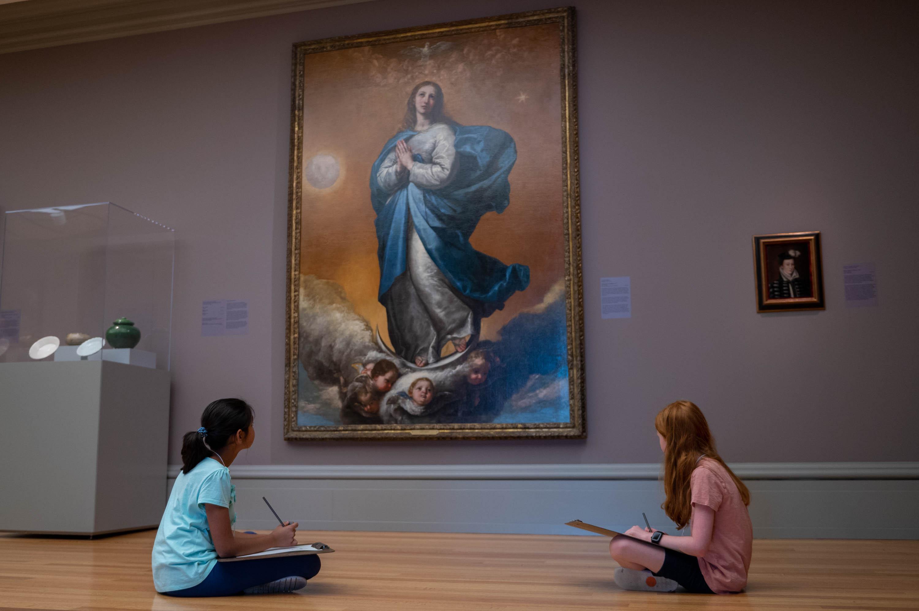 two campers in the galleries gathering inspiration from a large painting