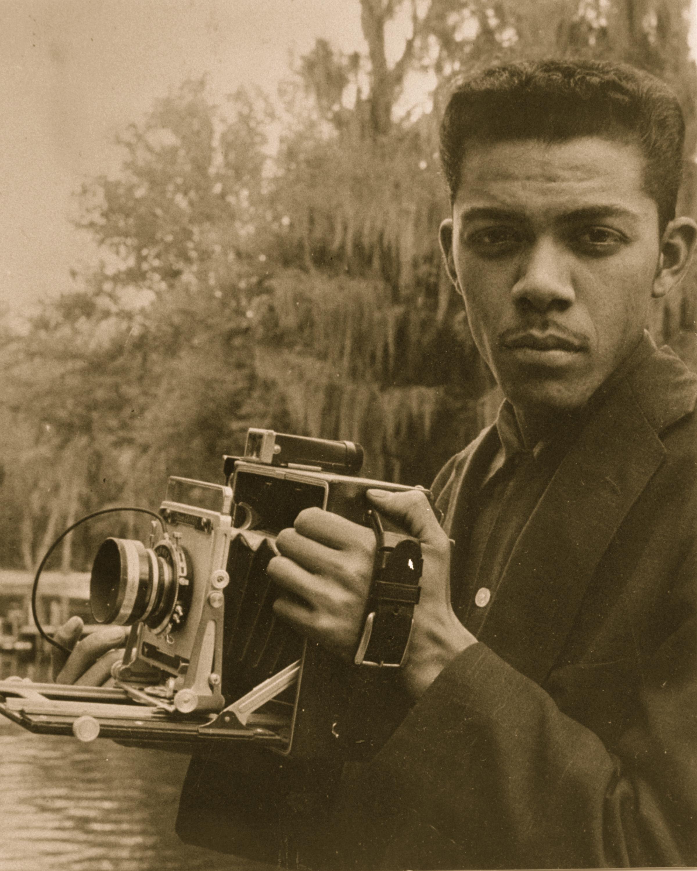 Cecil Williams holding a camera in a sepia-tone photograph