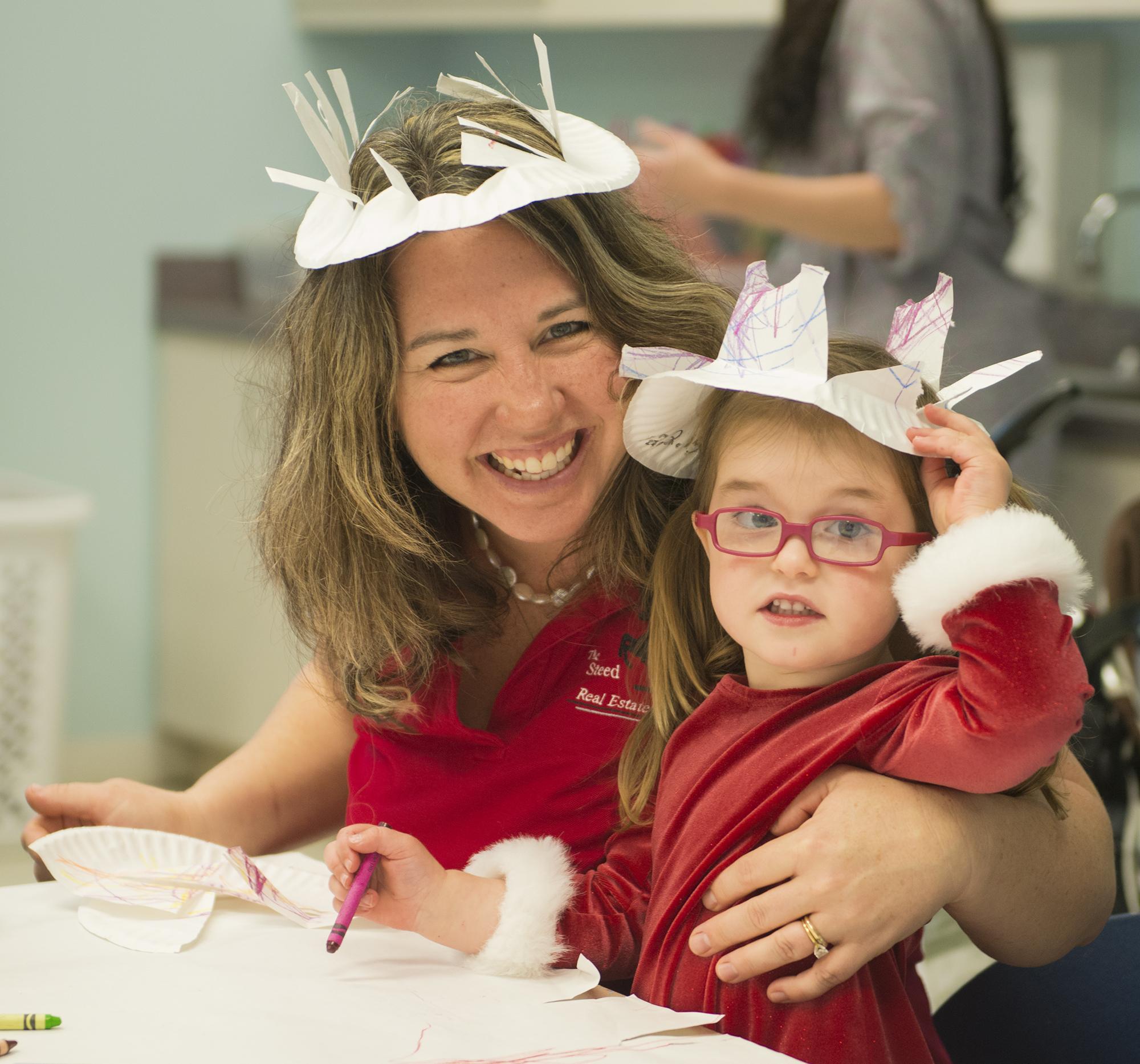 caregiver and child wearing handmade paper hats