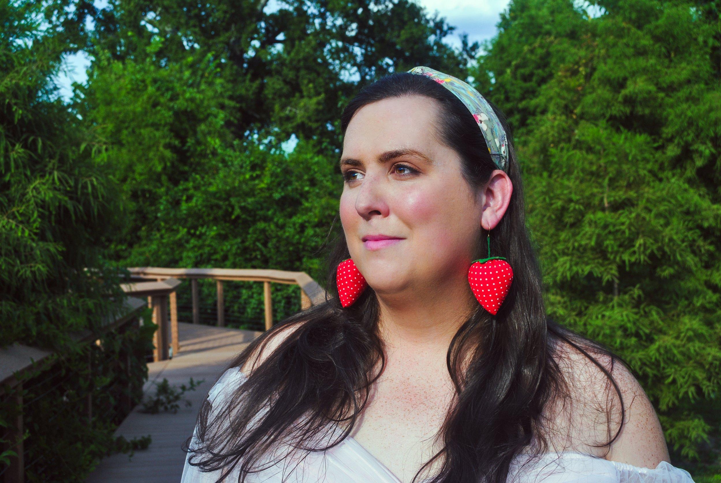 Evelyn Berry outside on a spring day wearing giant strawberry earrings