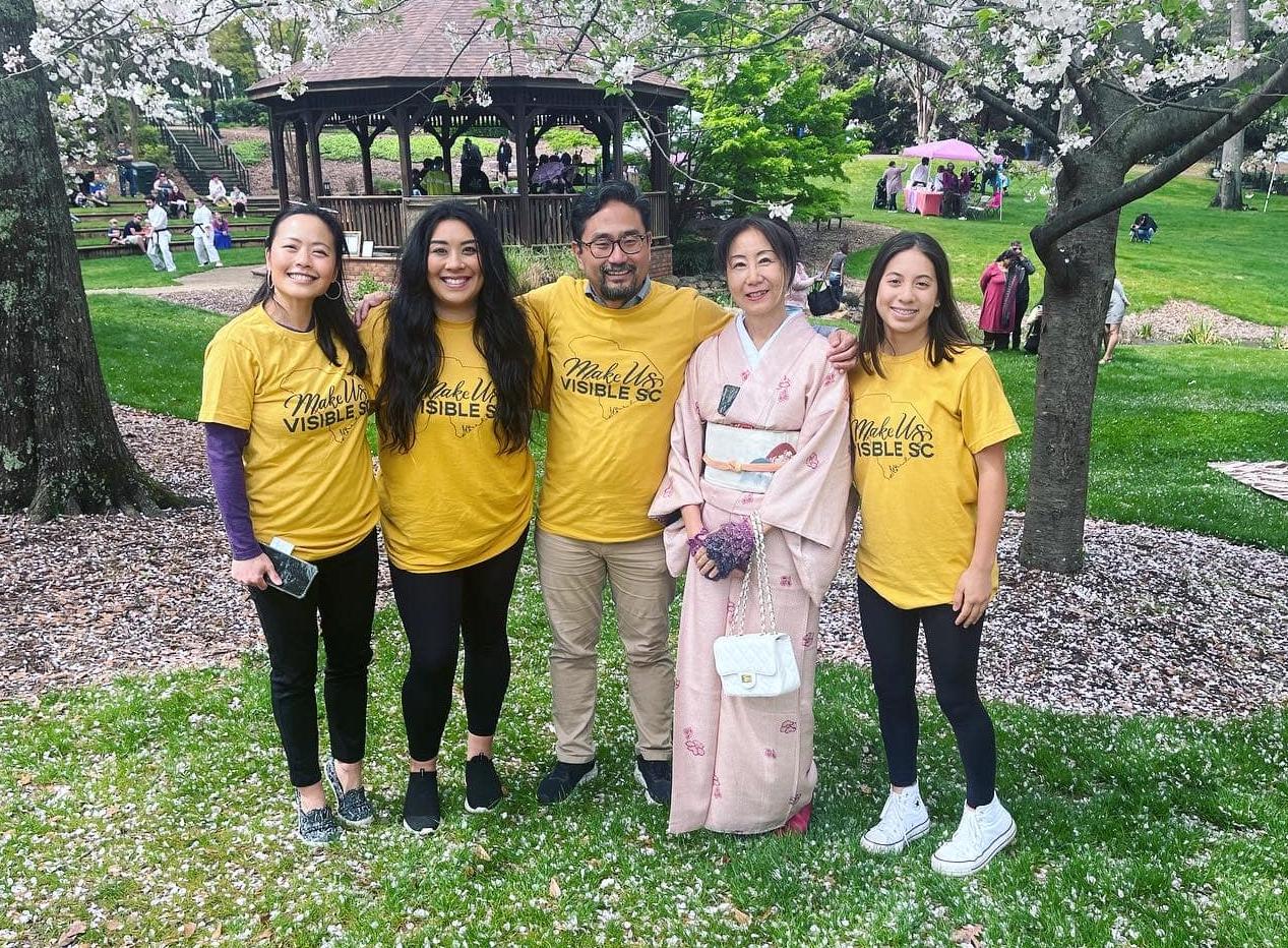 several members of Make Us Visible standing amongst cherry blossoms